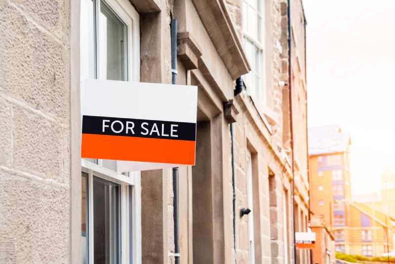 A "for sale" sign posted outside of a residential property