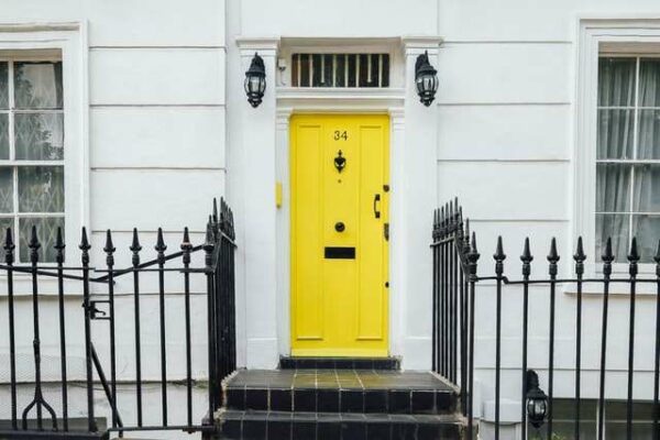 An image of a white building with a bright yellow front door