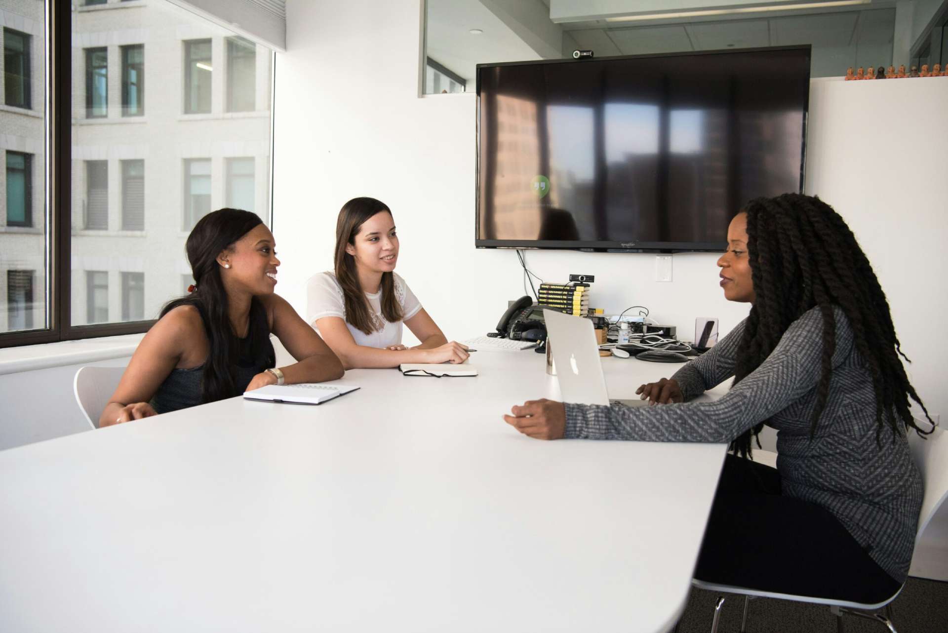 Three female colleagues have a meeting in a bright and modern office room