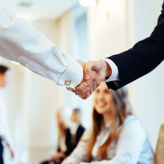Business Agreement Two business partners shake hands in a bright and modern office