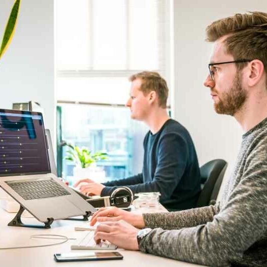 Employees Working Two male workers work at their desks in a bright and modern office