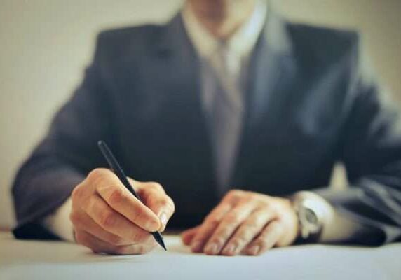 Legal Professional A closeup image of a legal professional signing a document at his desk